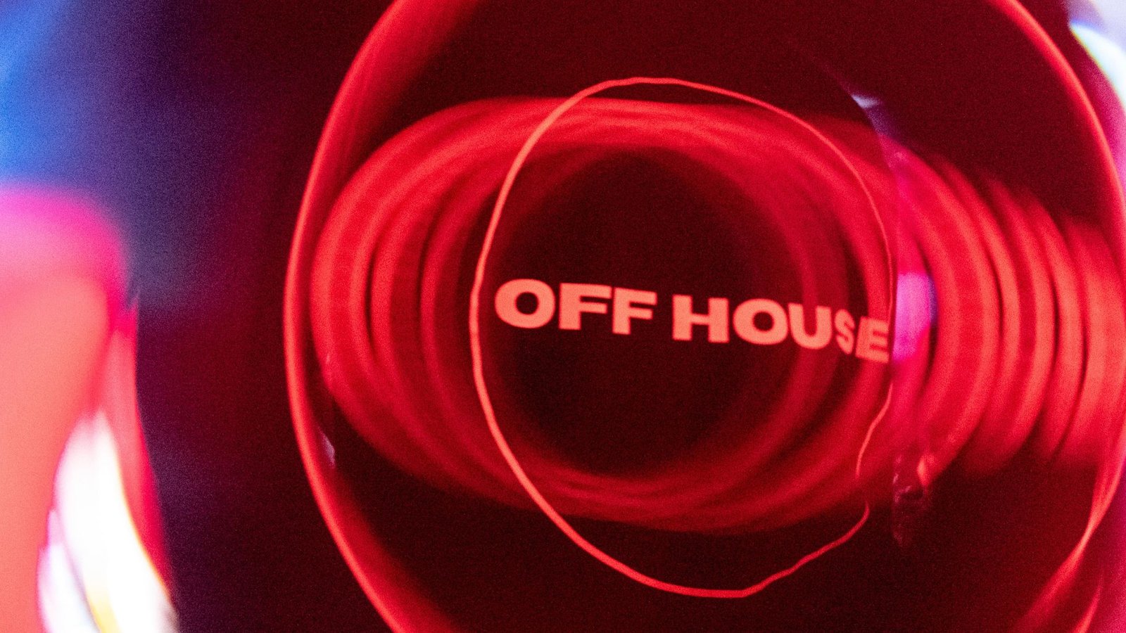 Crowd at an intimate underground OFF HOUSE event under warm red light.