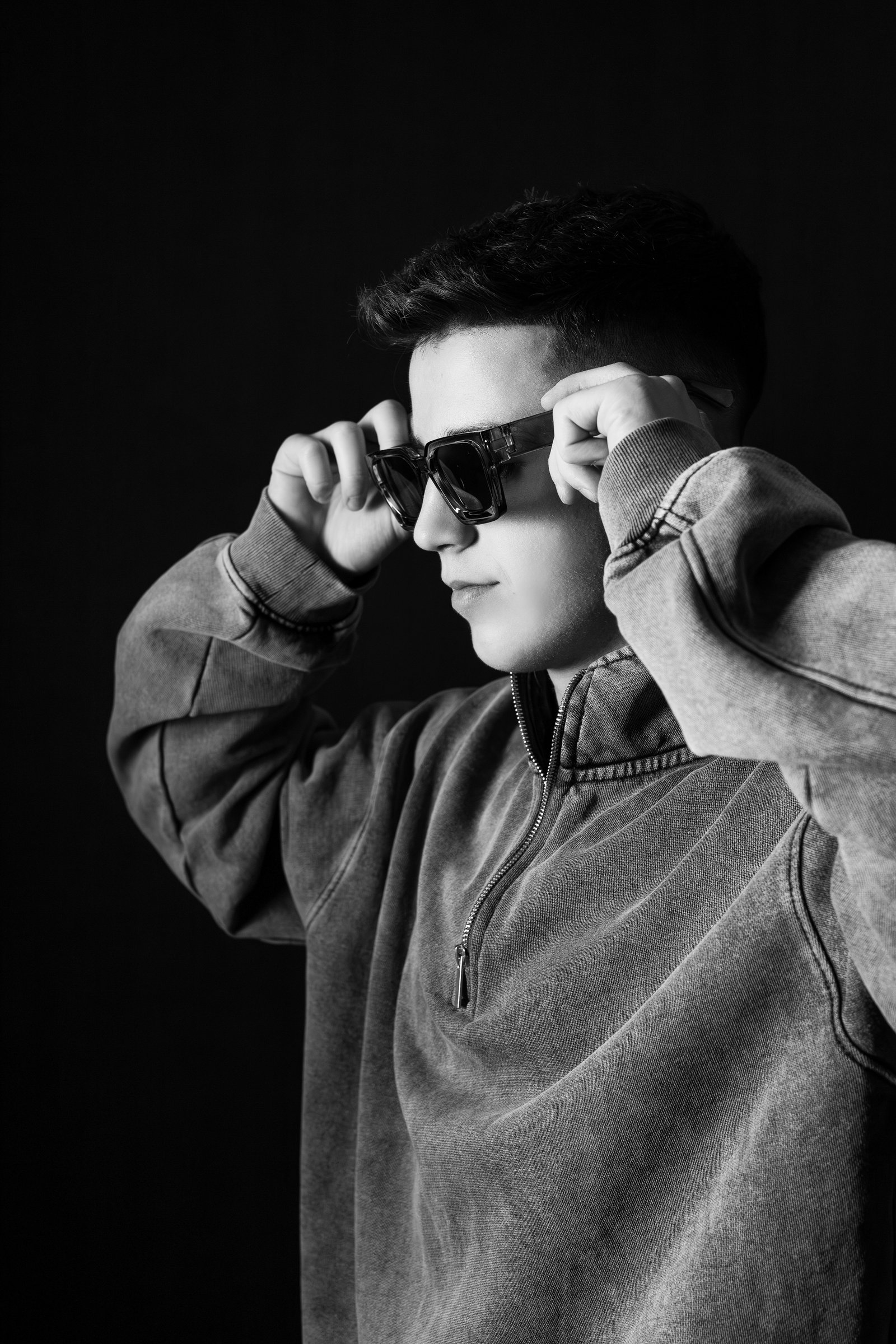 Editorial portrait of BEN D in a dark concrete room, lit from one side.